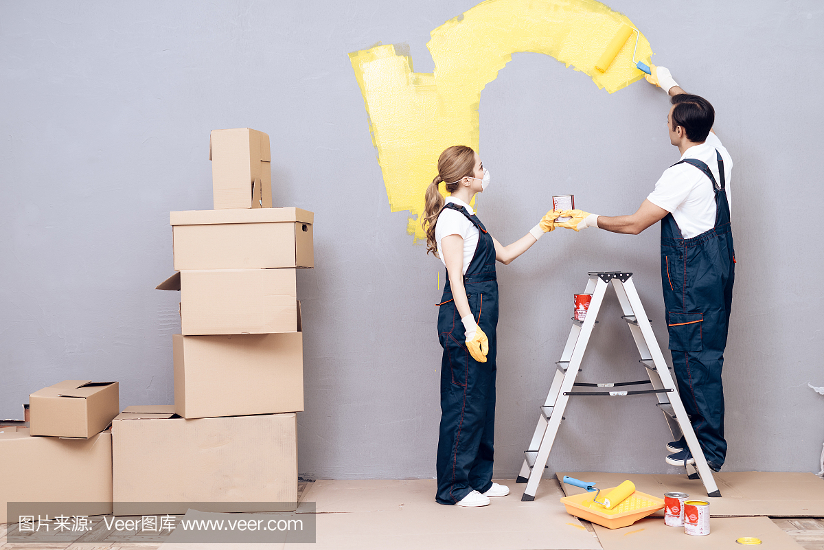 一名年轻女子和一名阿拉伯相貌的男子是一名画家。一个女人和一个男人正在刷墙。
