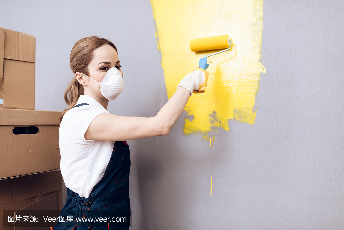 年轻女子经营着一间房子的油漆工。一位妇女正忙着刷墙。