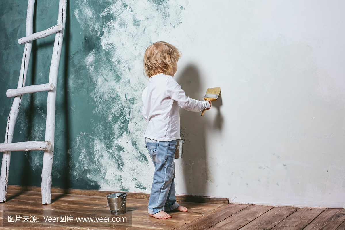 穿着牛仔裤又漂亮又快乐的小男孩在墙上画画